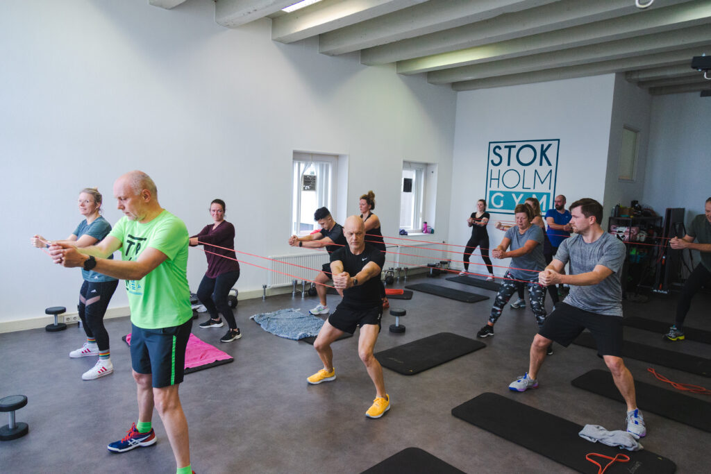 oefening in tweetallen met elastiek. Core recht en draaibeweging met gestrekte armen naar de zijkant.