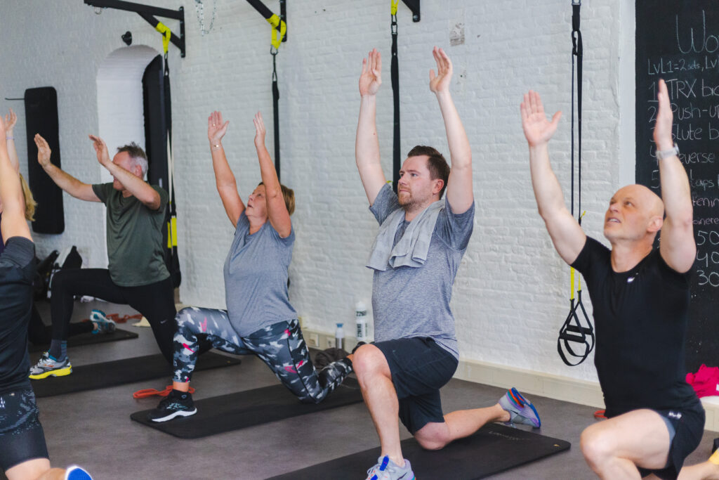 rekoefening op 1 knie met de handen omhoog om de spieren uit te rekken en sneller te herstellen van spierpijn