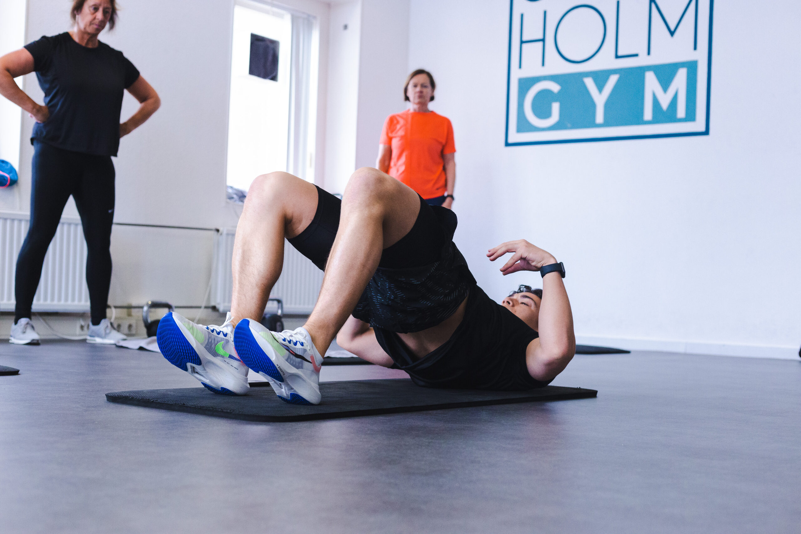 Oefening glute bridge uitgelegd en voorgedaan door sportinstructeur